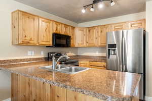 Kitchen featuring light brown cabinetry, appliances with stainless steel finishes, kitchen peninsula, and rail lighting