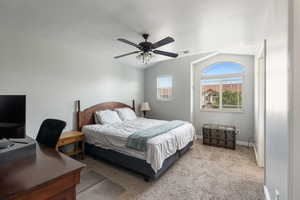 Bedroom with ceiling fan, vaulted ceiling, and light colored carpet