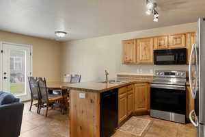 Kitchen featuring black appliances, rail lighting, sink, a textured ceiling, and kitchen peninsula