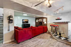 Living room featuring brick wall, a textured ceiling, hardwood / wood-style flooring, and rail lighting