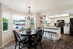 Dining room featuring sink, an inviting chandelier, a textured ceiling, and dark hardwood / wood-style floors