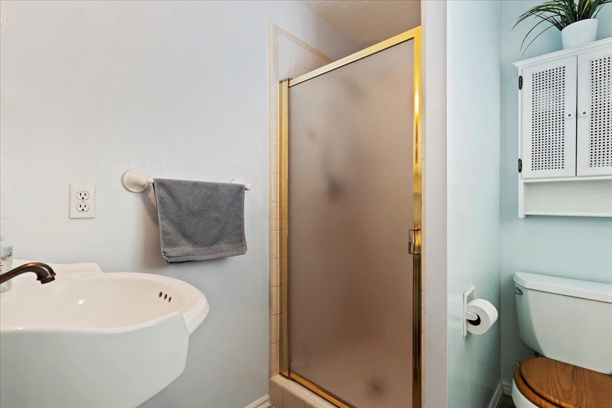 Bathroom featuring toilet, sink, and an enclosed shower