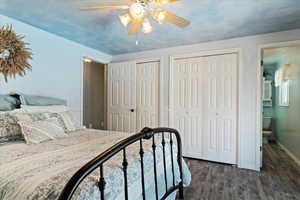 Bedroom featuring multiple closets, dark wood-type flooring, ceiling fan, and connected bathroom