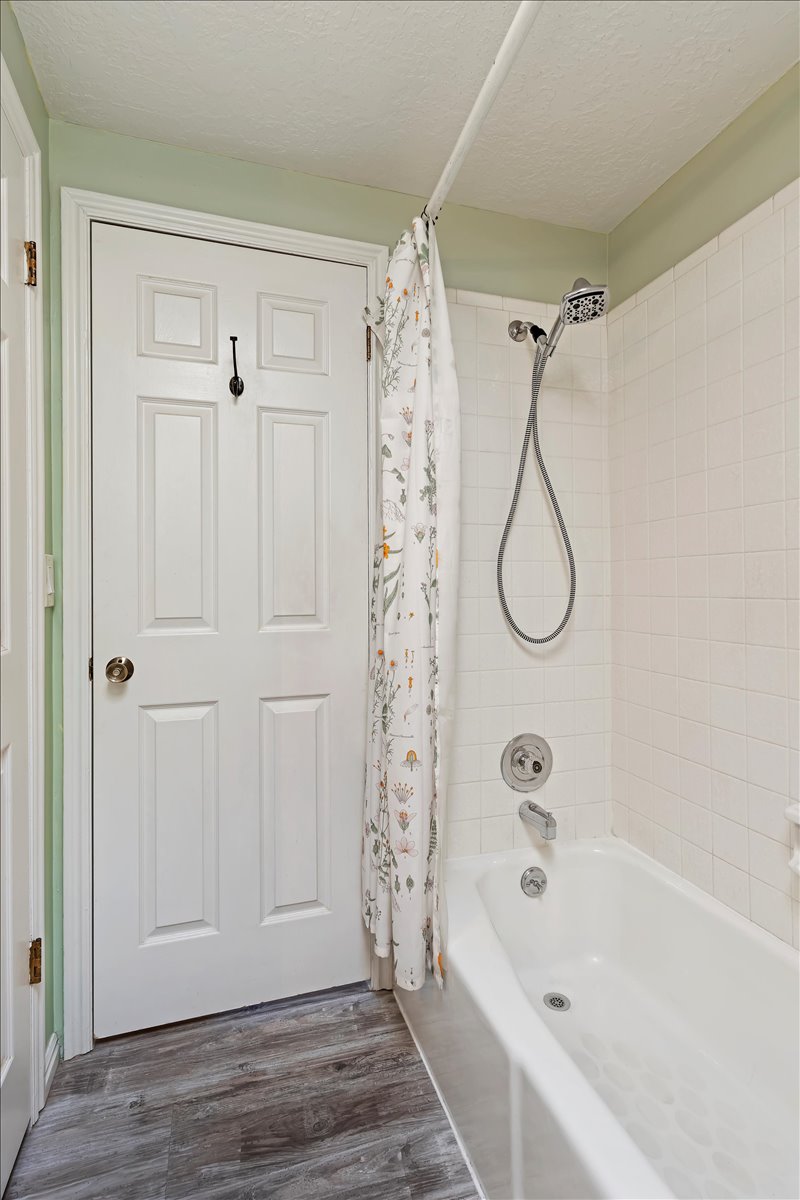 Bathroom featuring shower / bath combo, a textured ceiling, and hardwood / wood-style floors