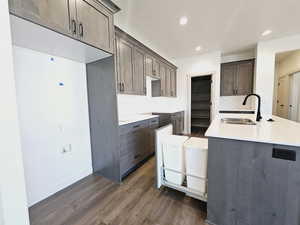 Kitchen with dark wood-type flooring, dark brown cabinetry, tasteful backsplash, and sink