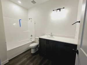 Full bathroom featuring hardwood / wood-style flooring, toilet, vanity, and tub / shower combination