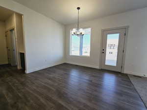 Unfurnished dining area with dark hardwood / wood-style floors and a chandelier