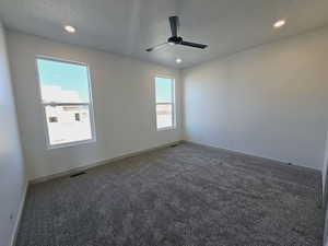 Primary bedroom with a textured ceiling, carpet flooring, a healthy amount of sunlight, and ceiling fan