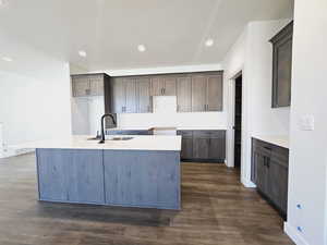 Kitchen with sink, dark hardwood / wood-style flooring, tasteful backsplash, and a kitchen island with sink