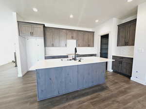 Kitchen featuring dark hardwood / wood-style flooring, sink, and an island with sink