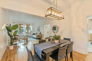 Dining space featuring a notable chandelier, crown molding, and light wood-type flooring