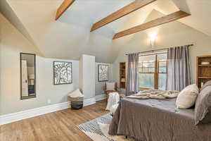 Bedroom with lofted ceiling with beams and light wood-type flooring