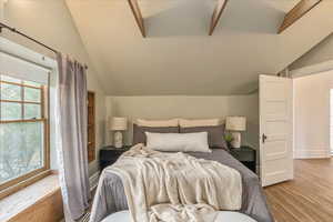 Bedroom featuring lofted ceiling with beams and light wood-type flooring