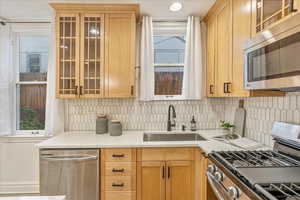 Kitchen featuring sink, appliances with stainless steel finishes, light stone countertops, and tasteful backsplash