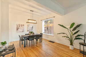 Dining area with ornamental molding, a notable chandelier, and light hardwood / wood-style flooring