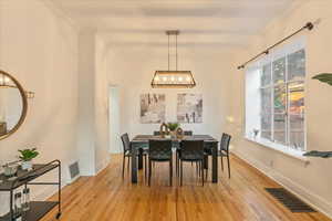 Dining room featuring an inviting chandelier, crown molding, and light hardwood / wood-style floors