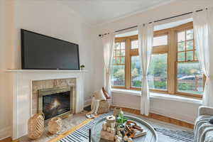 Living room with crown molding, a premium fireplace, and light wood-type flooring