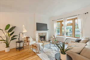 Living room with ornamental molding, a tiled fireplace, and light wood-type flooring