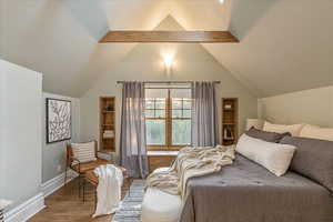 Bedroom with wood-type flooring and vaulted ceiling with beams