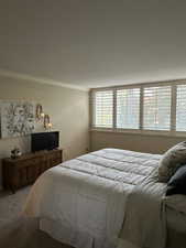 Bedroom with crown molding and light colored carpet