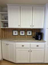 Bar with light stone countertops and white cabinetry