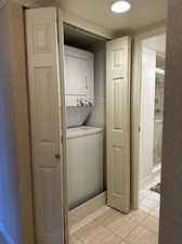 Laundry room with light tile patterned flooring and stacked washer and clothes dryer