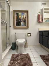 Bathroom featuring vanity, toilet, tile patterned floors, and walk in shower