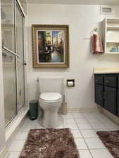 Bathroom with vanity, toilet, tile patterned flooring, and an enclosed shower