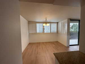 Empty room with light hardwood / wood-style floors and a notable chandelier