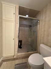 Bathroom with vanity, toilet, tile patterned floors, and a shower with door