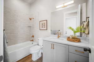 Full bathroom featuring toilet, wood-type flooring, vanity, and tiled shower / bath combo