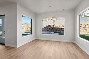 Unfurnished dining area with a wealth of natural light, a chandelier, and light hardwood / wood-style floors