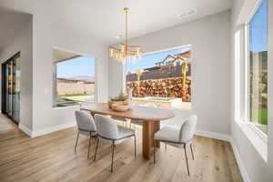 Dining area featuring a wealth of natural light, light hardwood / wood-style flooring, a mountain view, and a notable chandelier