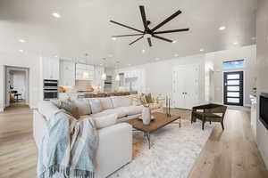 Living room with light hardwood / wood-style floors and ceiling fan