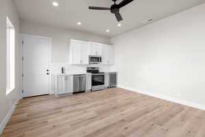 Kitchen featuring light hardwood / wood-style flooring, stainless steel appliances, white cabinetry, and ceiling fan