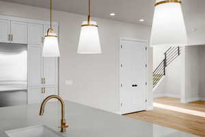 Kitchen with stainless steel built in refrigerator, white cabinetry, pendant lighting, and light hardwood / wood-style flooring