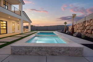 Pool at dusk featuring an in ground hot tub and a patio area