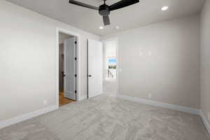 Unfurnished bedroom featuring light carpet and ceiling fan