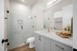 Bathroom with vanity, hardwood / wood-style flooring, toilet, and an enclosed shower