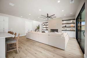 Living room featuring a tile fireplace, light hardwood / wood-style floors, and ceiling fan