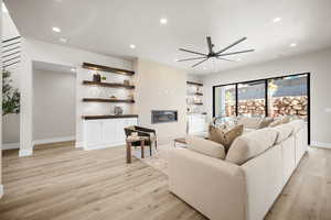 Living room featuring a tile fireplace, ceiling fan, and light wood-type flooring