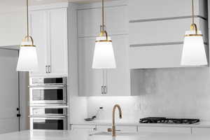 Kitchen featuring appliances with stainless steel finishes, sink, tasteful backsplash, and white cabinetry