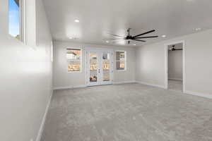 Unfurnished room with light carpet, french doors, and ceiling fan