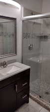 Bathroom with tile patterned flooring, vanity, and an enclosed shower