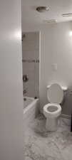 Bathroom with tiled shower / bath combo, toilet, tile patterned floors, and a textured ceiling