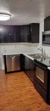 Kitchen featuring light hardwood / wood-style floors, a textured ceiling, and stainless steel appliances