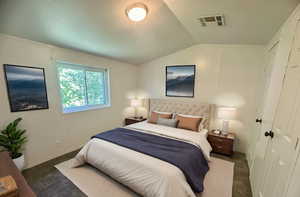 Bedroom with dark colored carpet and vaulted ceiling. Virtually staged