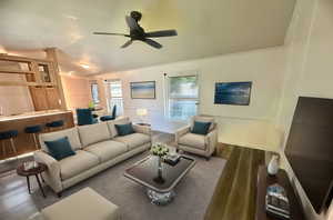 Living room featuring wood-type flooring and ceiling fan. Virtually staged