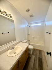 Full bathroom featuring vanity, hardwood / wood-style flooring,  shower combination, and toilet