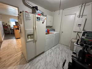 Laundry area with cabinets, washing machine and dryer, electric panel, and light tile patterned floors